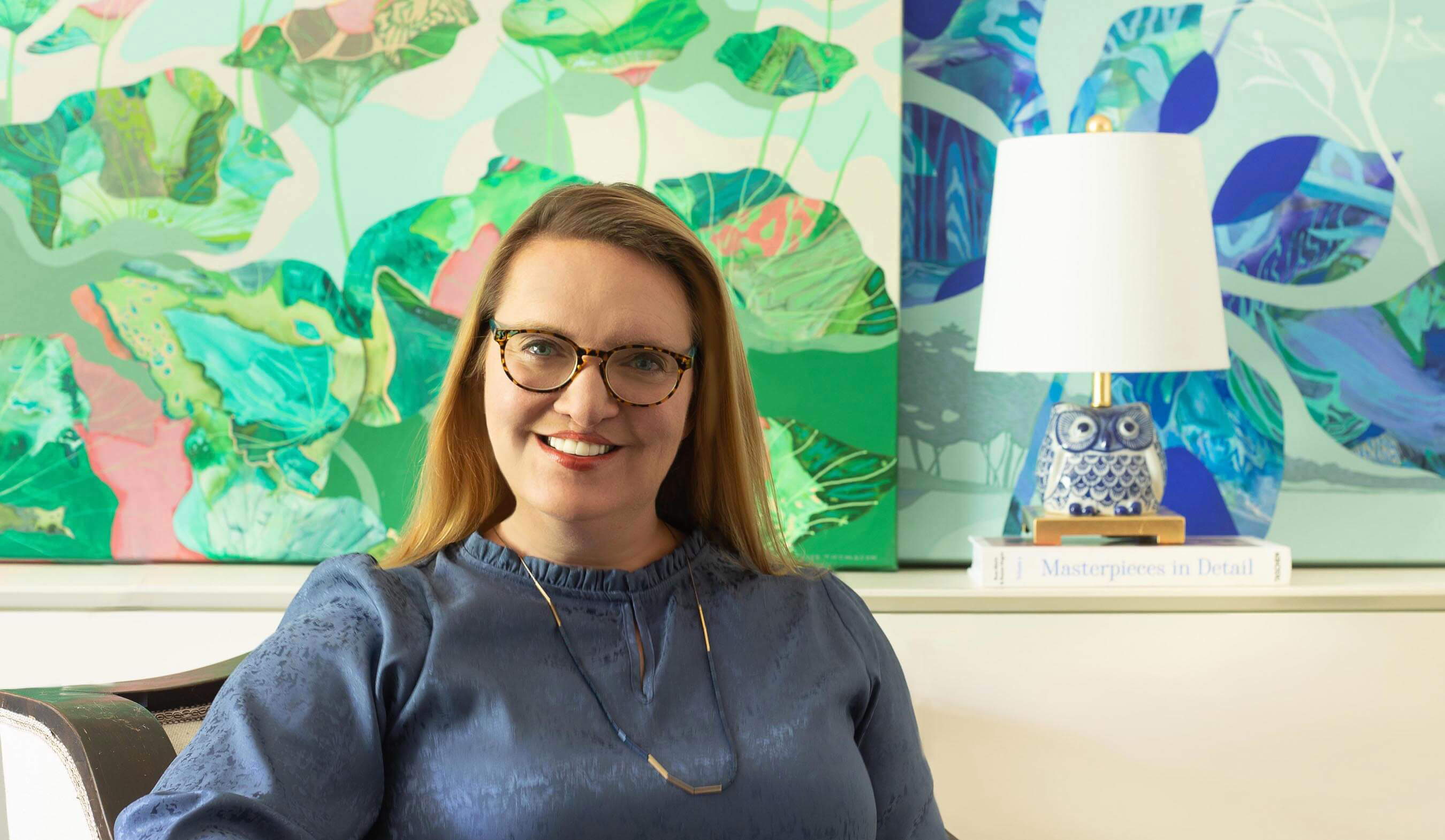 photograph of artist Elise Thomason in front of two abstract paintings